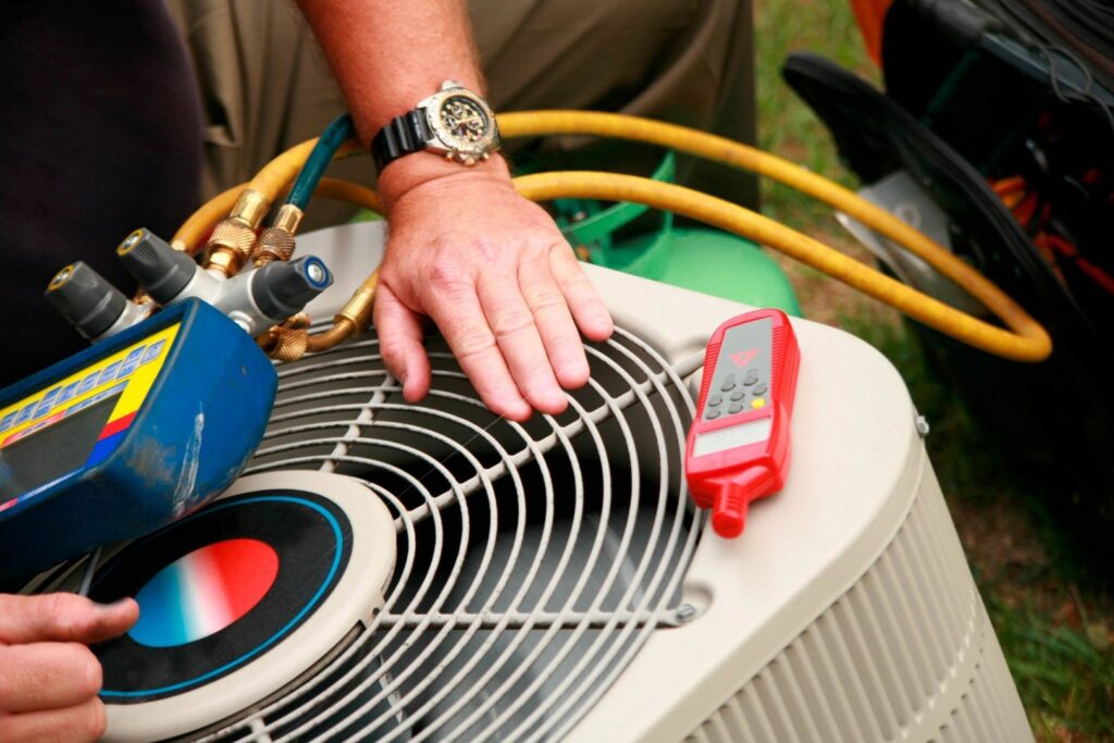 An HVAC technician servicing an outdoor air conditioning unit with gauges for Butte Heating & Cooling in Rapid City, SD.