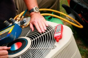 An HVAC technician servicing an outdoor air conditioning unit with gauges for Butte Heating & Cooling in Rapid City, SD.