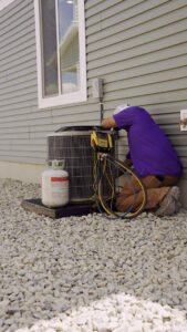 An HVAC technician from CSA HVAC Services servicing an outdoor AC unit with gauges in Orem, UT.