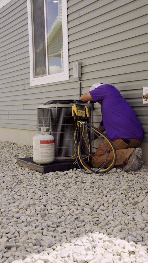 An HVAC technician from CSA HVAC Services servicing an outdoor AC unit with gauges in Orem, UT.