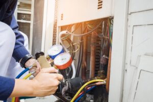 An HVAC technician servicing an outdoor air conditioning unit with gauges for Cyber Heating and Cooling in Bloomington, MN.