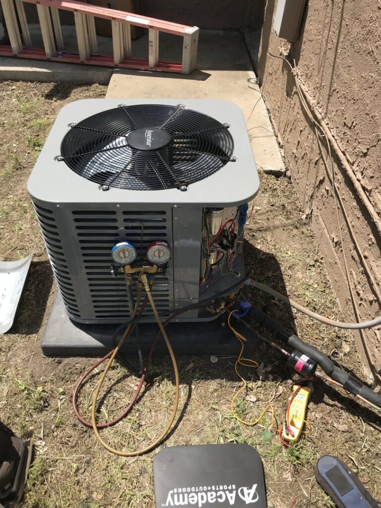 An HVAC technician connecting gauges to an outdoor AC unit for service by Epic Heating & Cooling in Wichita, KS.