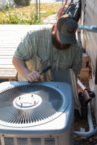 An HVAC technician servicing an outdoor air conditioning unit with tools for Equality State Heating & Cooling in Casper, WY.