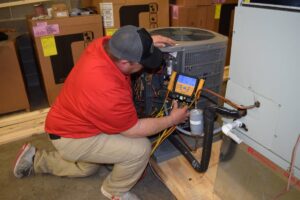 An HVAC technician from Family Heating & Air Conditioning servicing an outdoor AC unit in Indianapolis, IN.