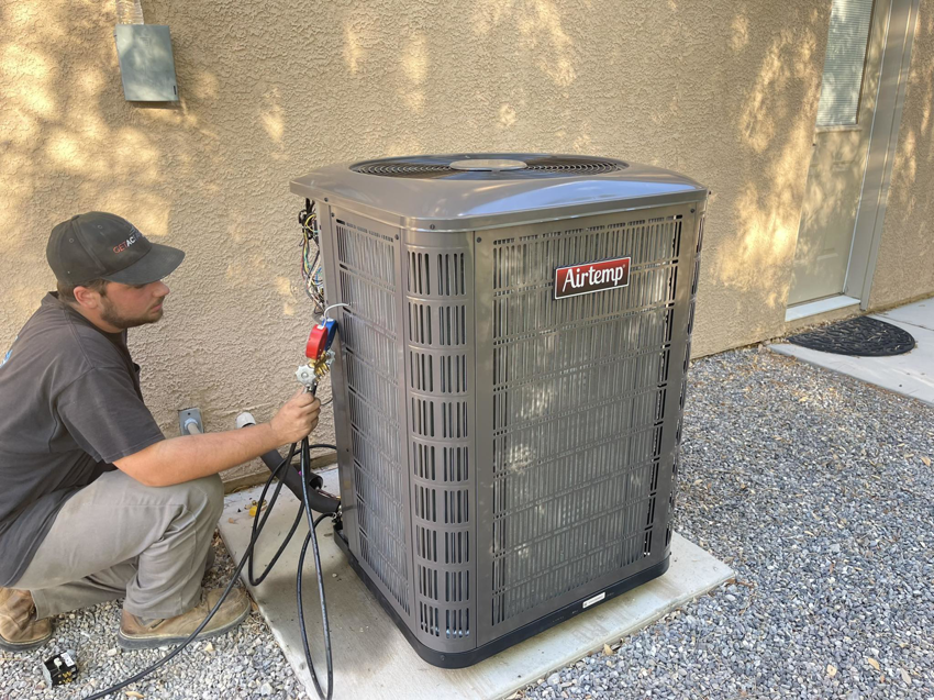 An HVAC technician from GETACFAST.com servicing an outdoor air conditioning unit in Henderson, NV.