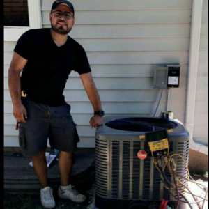 An HVAC technician servicing an outdoor air conditioning unit at a home in Waukegan, IL, by JRod's Heating & Cooling.
