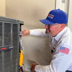 An HVAC technician servicing an outdoor AC unit with a multimeter for Larson Air Conditioning in Scottsdale, AZ