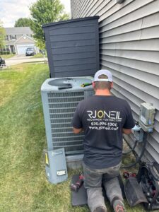 An R.J. O'Neil Inc. HVAC technician servicing an outdoor air conditioning unit in Montgomery, IL.