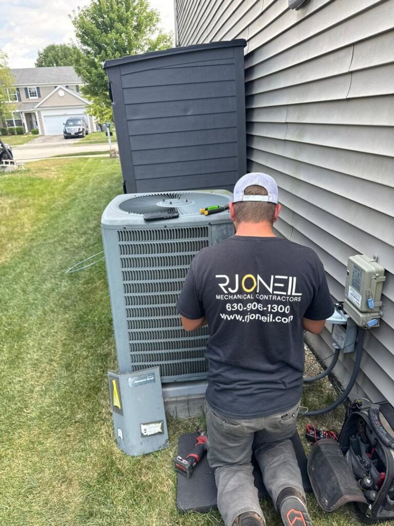 An R.J. O'Neil Inc. HVAC technician servicing an outdoor air conditioning unit in Montgomery, IL.