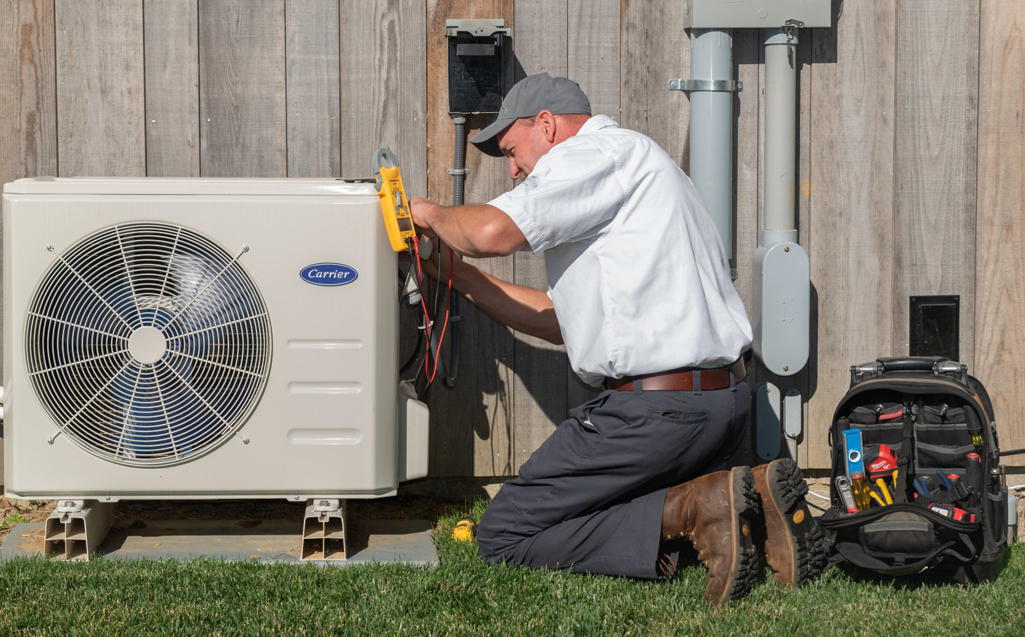 An HVAC technician servicing an outdoor Carrier air conditioning unit for RSC Heating and Air Conditioning in Lancaster, PA.