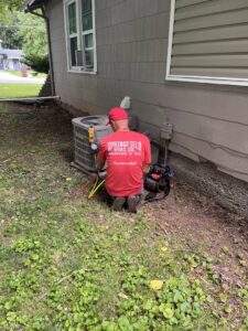 An HVAC technician from Springfield HVAC Company servicing an outdoor air conditioning unit in Springfield, MO.