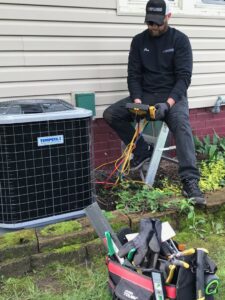 An HVAC technician from Wight's Heating & Air Conditioning servicing an outdoor AC unit in Rockford, IL
