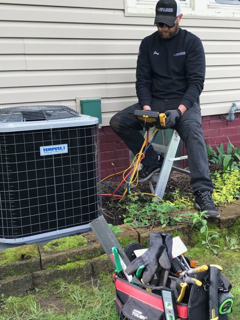 An HVAC technician from Wight's Heating & Air Conditioning servicing an outdoor AC unit in Rockford, IL