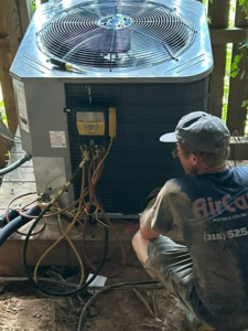 An Air Care Heating and Cooling Services technician servicing an outdoor AC unit with gauges in Shreveport, LA.