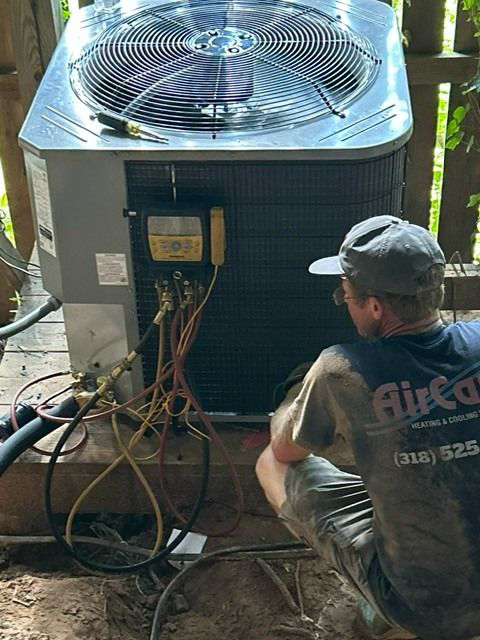 An Air Care Heating and Cooling Services technician servicing an outdoor AC unit with gauges in Shreveport, LA.