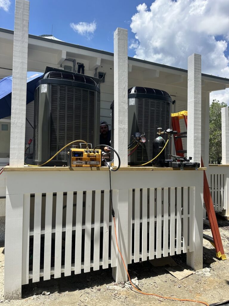 An HVAC technician servicing outdoor AC condenser units with tools for AC Heating and Air Conditioning Services in Charleston, SC.