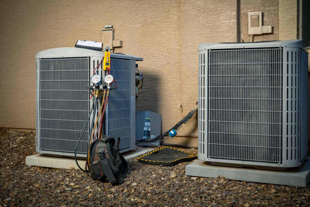 An HVAC technician servicing outdoor AC units with gauges and tools at AVI Heating & Cooling in Surprise, AZ
