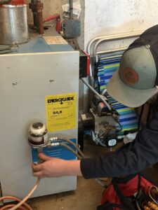 An HVAC technician from Black Oak HVAC servicing a boiler or water heater unit in Derry, NH