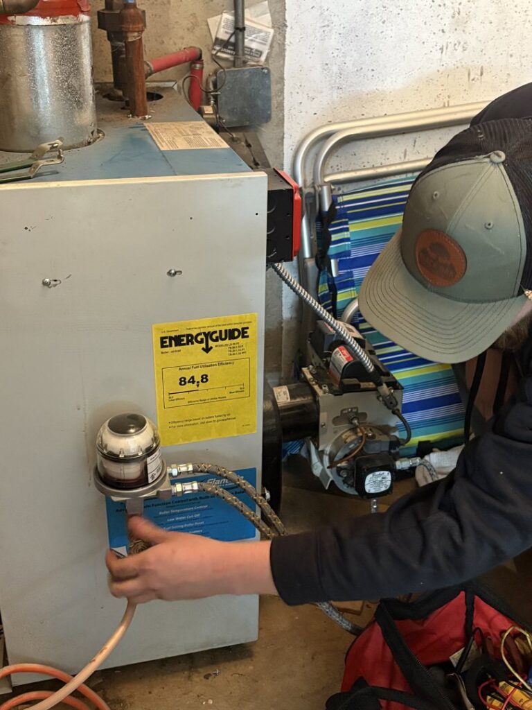 An HVAC technician from Black Oak HVAC servicing a boiler or water heater unit in Derry, NH