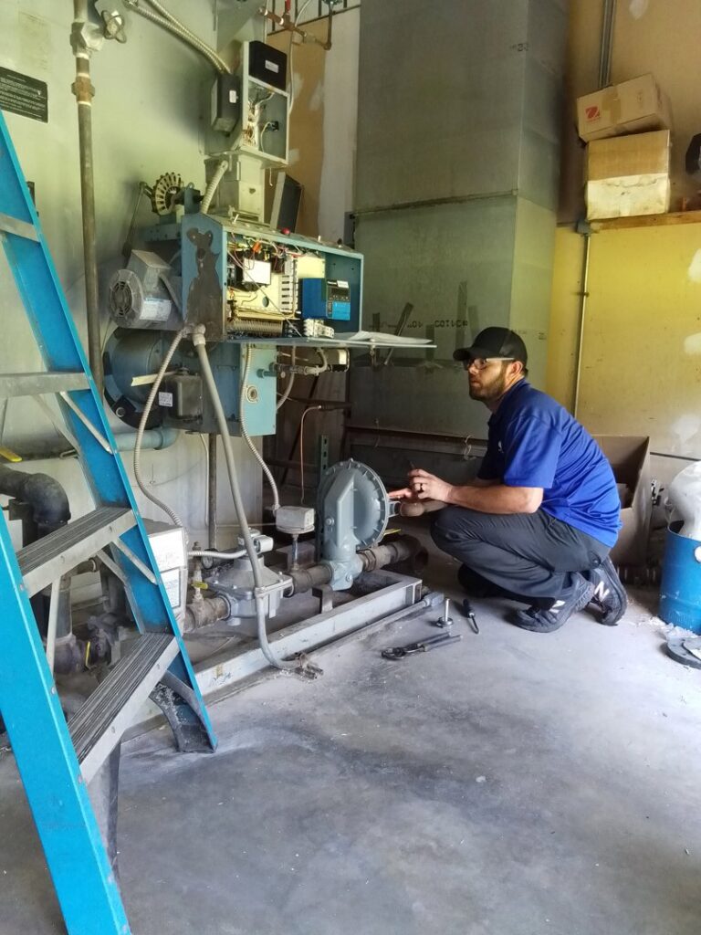 A CM3, Inc. HVAC technician servicing a commercial boiler or furnace unit in Wichita, KS.