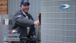 An HVAC technician servicing a Carrier air conditioner unit for Specialty Heating and Cooling in Portland, OR.