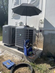 A Vanessa Service HVAC technician servicing Carrier outdoor air conditioning units with tools and gauges in Falls Church, VA.