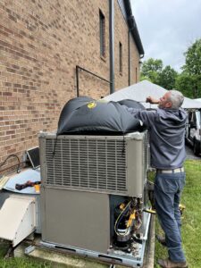 An HVAC technician performing service on a large commercial outdoor AC unit for Radiant Heating & Cooling in Fishers, IN.