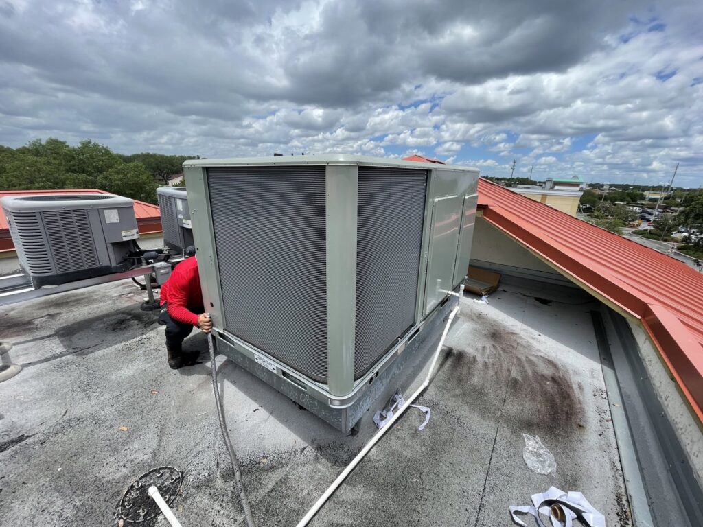 An HVAC technician servicing a large commercial rooftop unit for Blue Air Heating and Cooling in Orlando, FL.
