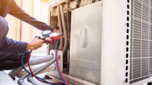An HVAC technician servicing a commercial outdoor unit with gauges for Air Control Heating & Cooling LLC in Schererville, IN.