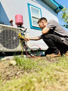 A Best Heat & Air technician servicing an outdoor HVAC condenser unit with gauges in Tacoma, WA.