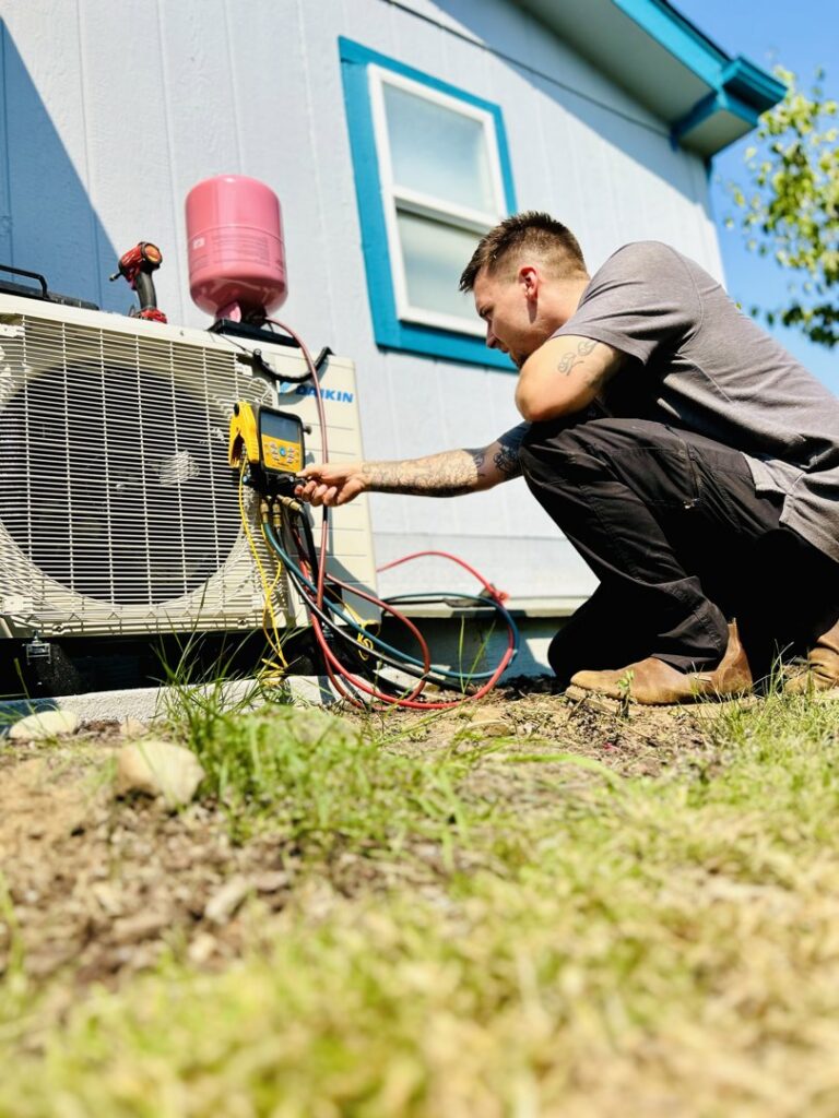 A Best Heat & Air technician servicing an outdoor HVAC condenser unit with gauges in Tacoma, WA.