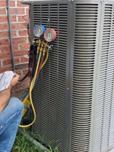 An HVAC technician servicing an outdoor condenser unit with manifold gauges for Brady Air & Home Repair LLC in Asheboro, NC.