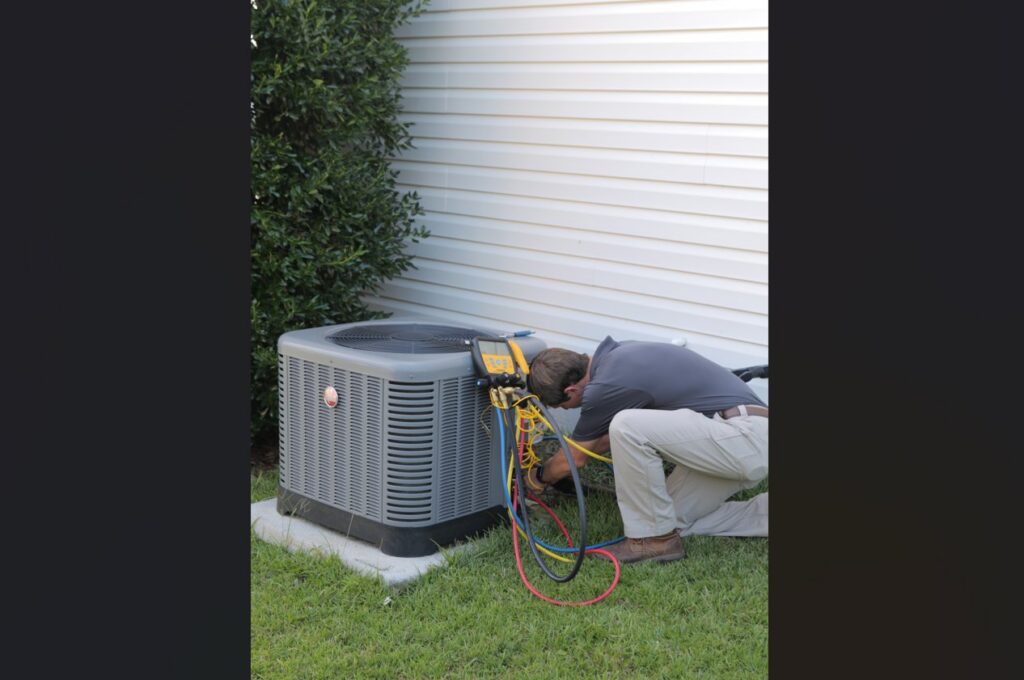 An HVAC technician servicing an outdoor condenser unit with gauges for Joe's Heating & Air Repair LLC in Surf City, NC