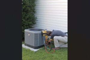 An HVAC technician servicing an outdoor condenser unit with gauges for Joe's Heating & Air Repair LLC in Surf City, NC