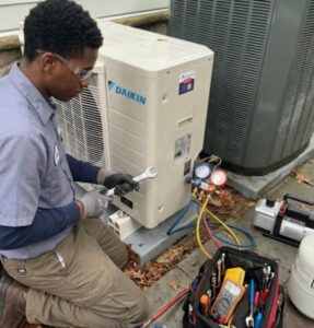 An HVAC technician servicing a Daikin outdoor unit with a wrench and gauges for RESTQ HVAC Repairs & Services in Rockville, MD.