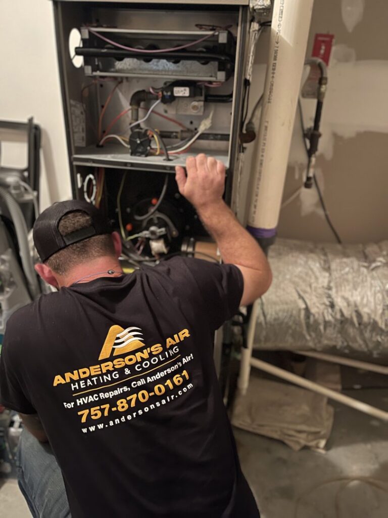 An HVAC technician servicing an indoor furnace or air handler unit for Anderson's Air in Newport News, VA
