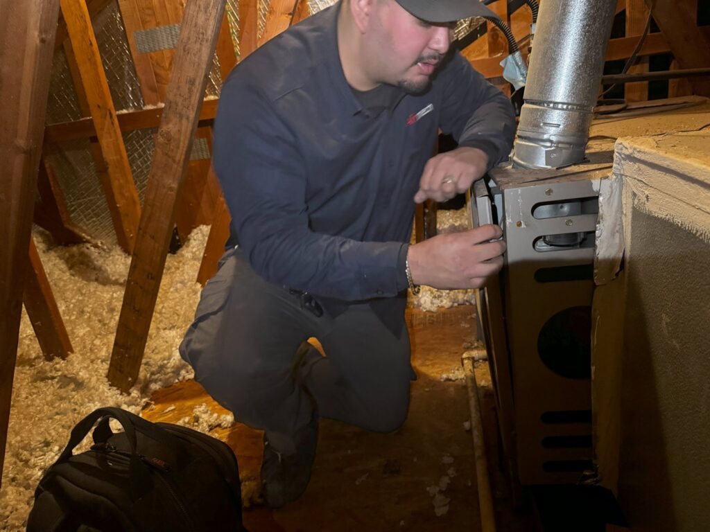 An Airmech Heating and Air Conditioning technician servicing a furnace in an attic in Elk Grove, CA.
