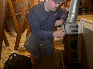 An Airmech Heating and Air Conditioning technician servicing a furnace in an attic in Elk Grove, CA.