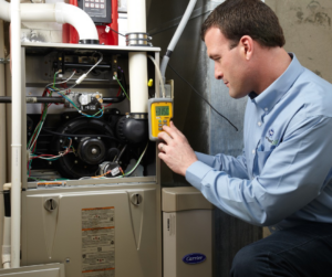 An HVAC technician servicing a Carrier furnace unit with a diagnostic tool at Berkeley Heating and Air Conditioning in Hanahan, SC