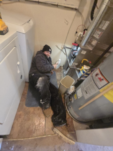 A Comfort-Tech llc technician servicing a furnace and water heater in a utility room in Alexandria, VA.