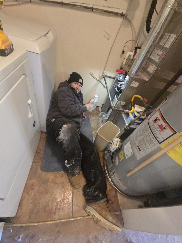 A Comfort-Tech llc technician servicing a furnace and water heater in a utility room in Alexandria, VA.