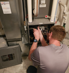 An HVAC technician servicing an indoor furnace or air handler unit at a client's home by EZ AIR HVAC in San Antonio, TX