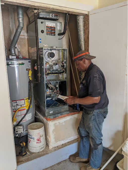 An HVAC technician servicing a furnace unit at a client's home for Goodpaster's Mechanical, Inc. in Broken Arrow, OK.