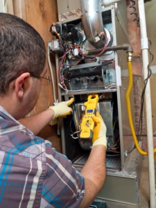 An HVAC technician servicing an indoor furnace or air handler unit for Lipovic Heating & Cooling in Mesa, AZ.