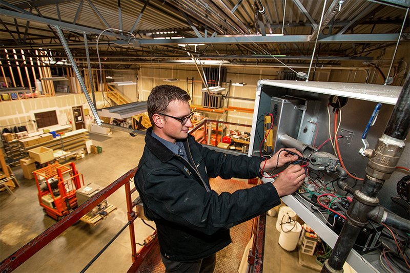 An HVAC technician servicing a furnace unit for Paul's Heating & Air Conditioning in Virginia Beach, VA.