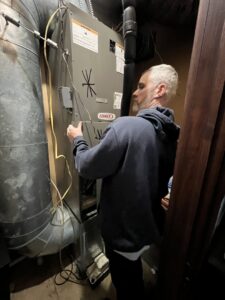 An HVAC technician performing maintenance on a Lennox furnace in a residential home for Radiant Heating & Cooling in Fishers, IN.