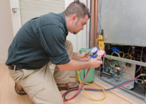 An HVAC technician servicing an indoor furnace unit with manifold gauges for Rhode Island HVAC Services in Providence, RI.