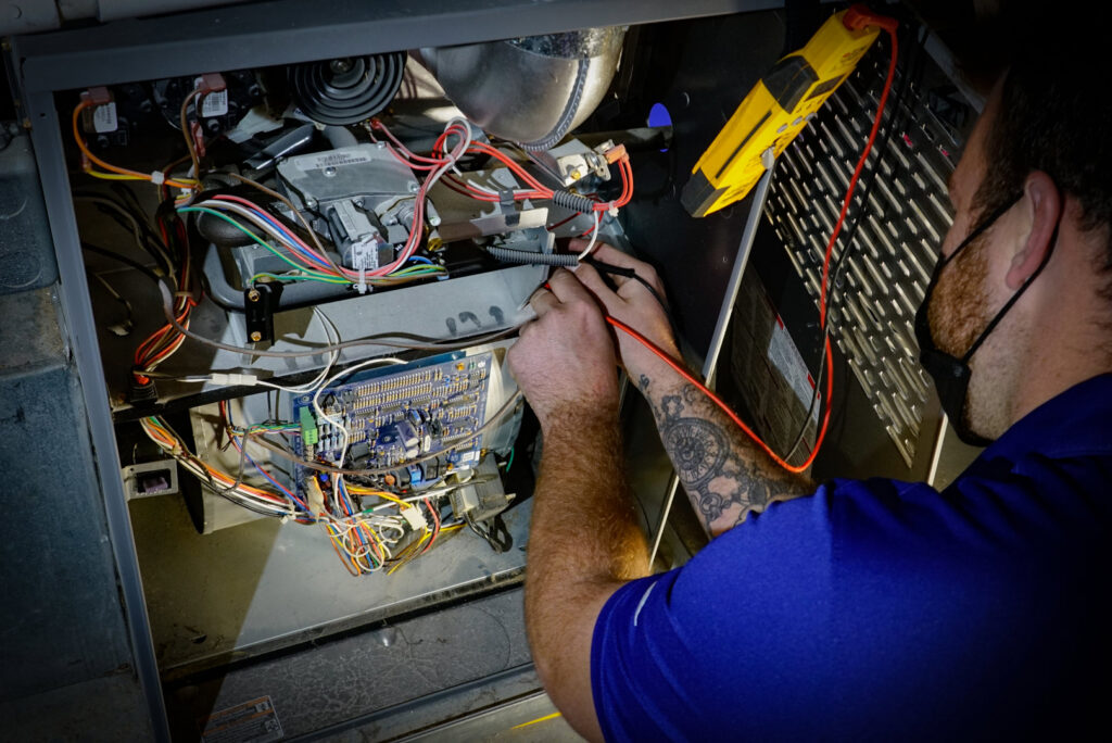 A SANKS Mechanical technician performing diagnostics and service on the internal components of a furnace unit in Philadelphia, PA.
