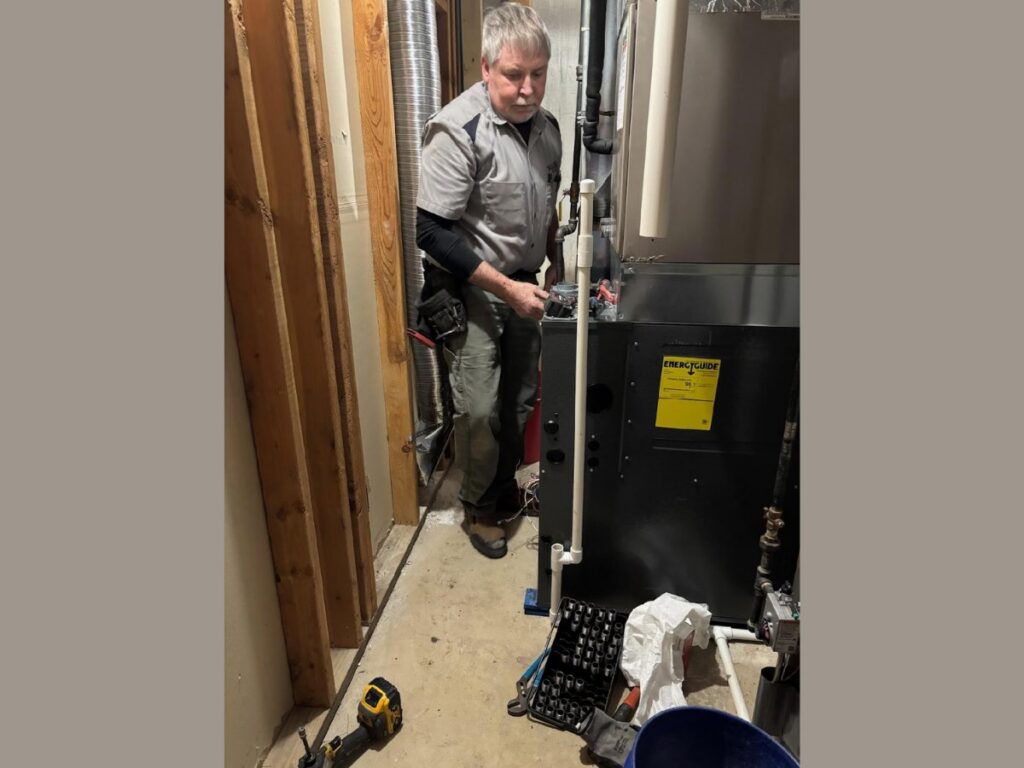 An HVAC technician servicing a large furnace or air handler unit for Thrasher Service Corp in Des Moines, IA.