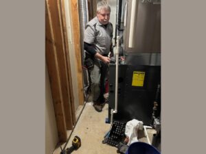 An HVAC technician servicing a large furnace or air handler unit for Thrasher Service Corp in Des Moines, IA.